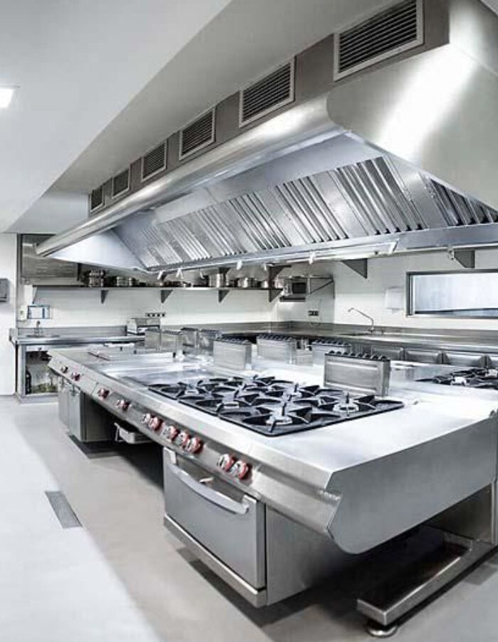Cozinha industrial em aço inox com coifa e fogões, limpa e organizada